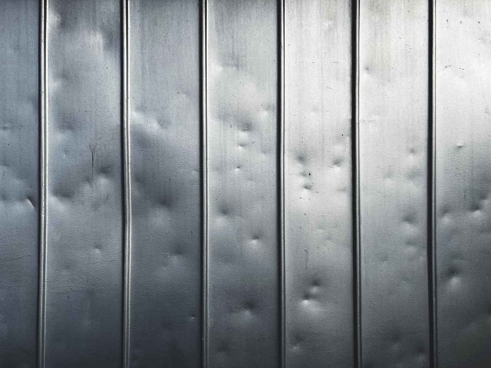 A black metal roof with dents from hail damage.