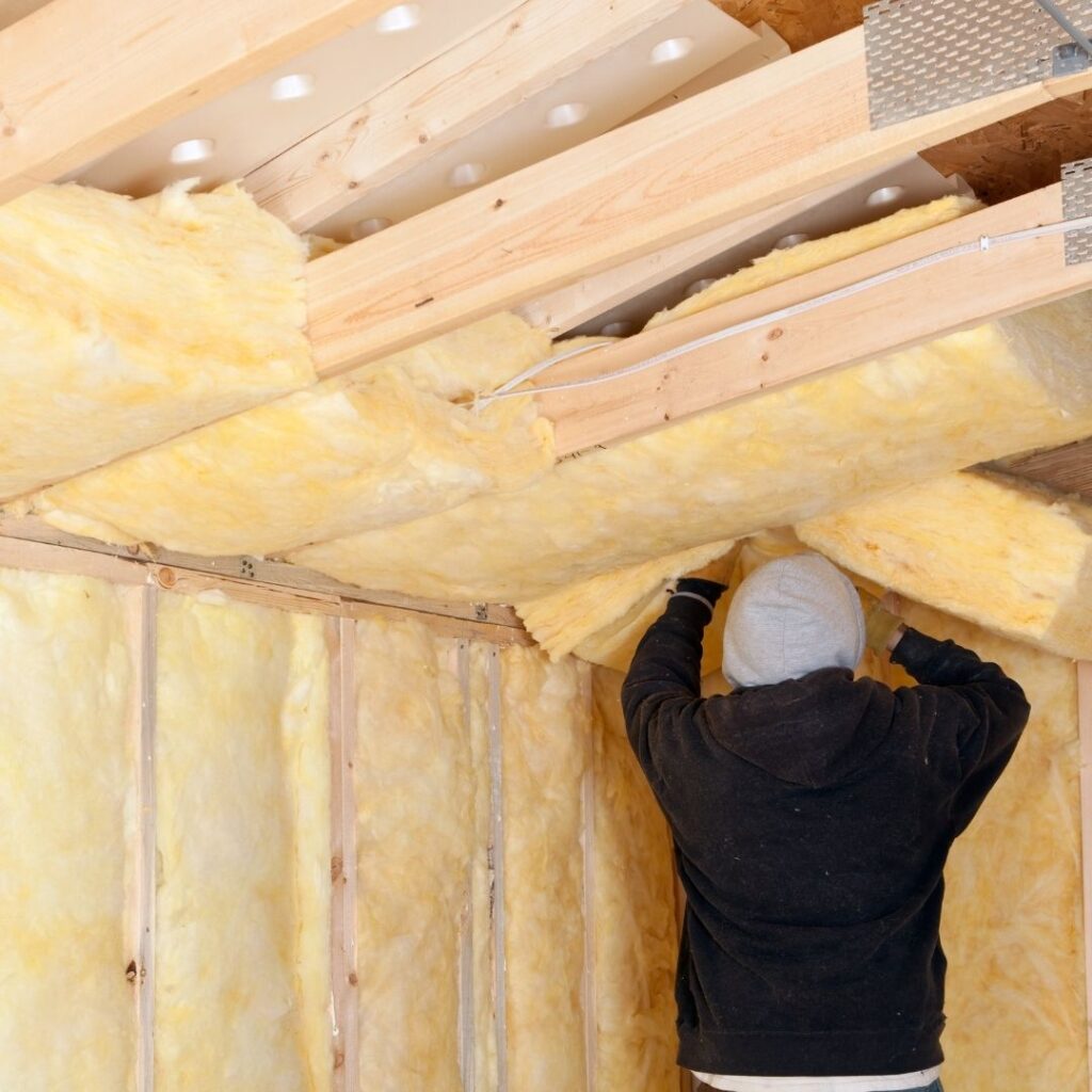 A worker installs insulation on a roof.