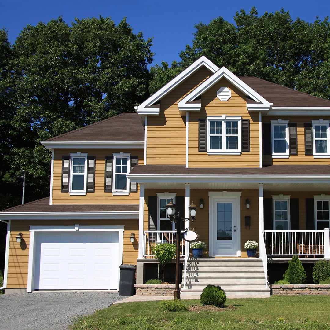 A beautiful mustard-yellow home with a tidy front yard and new roof.