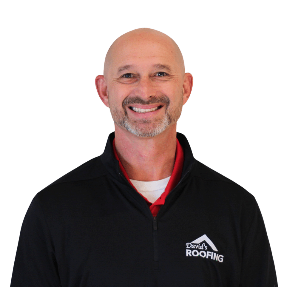 A smiling man with a bald head and goatee wears a black pullover with "David's Roofing" logo over a red shirt.