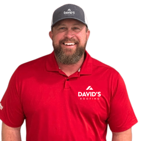 Man wearing a red polo shirt and gray cap with "David's Roofing" logo, smiling, standing against a plain light background.